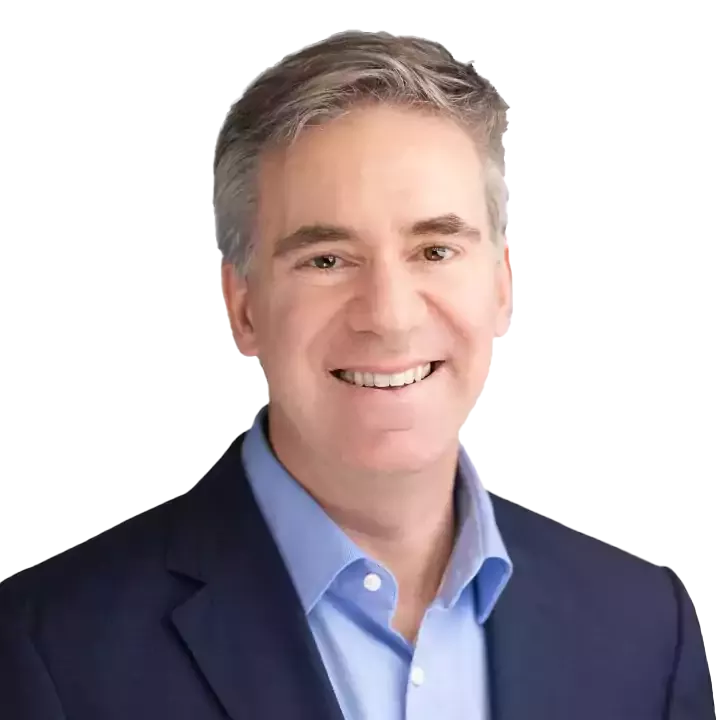 Smiling man in a suit with a blue shirt, against a white background.