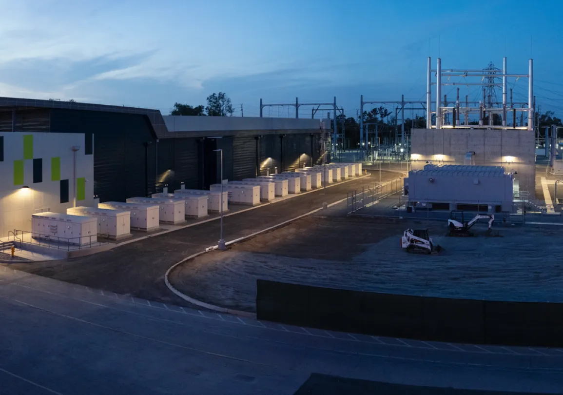 A panoramic view of an industrial facility at dusk, featuring a large building with a modern design and multiple utility boxes lined up outside.