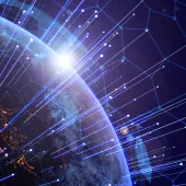 A view of Earth from space with a digital network overlay. Bright lines and nodes represent global connectivity, while city lights are visible on the planet's surface. The sun is rising on the horizon, casting a glow over the scene.