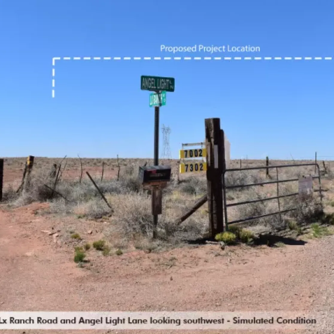 A rural intersection with dirt roads, featuring a street sign for Angel Light Lane and Lx Ranch Road. A dashed line marks the proposed project location in the distant sky. The area is flat with sparse vegetation and fenced boundaries. A sign with numbers 7002 and 7302 is visible near the gate.
