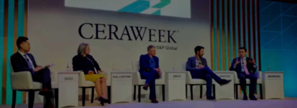 Five people sit on a panel stage at CERAWeek by S&P Global. They are seated in chairs with nameplates: Zhou, Ballentine, Smith, Manous, and Moreno. The backdrop features the CERAWeek logo and geometric designs. The panelists are engaged in discussion, with one speaking and others listening.