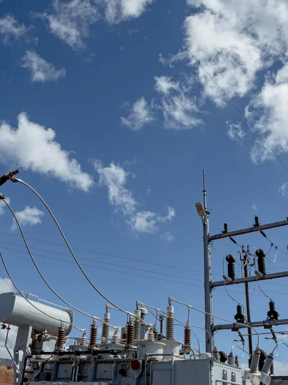 Electrical substation with transformers and power lines under a blue sky with scattered clouds.