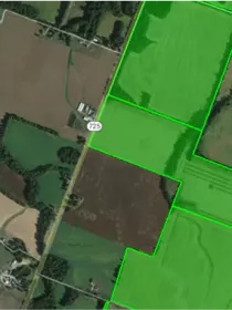 Aerial view of farmland with green boundary lines highlighting specific plots. A road marked with the number 725 runs through the area.