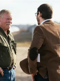 Two men standing outdoors having a conversation in front of solar panels