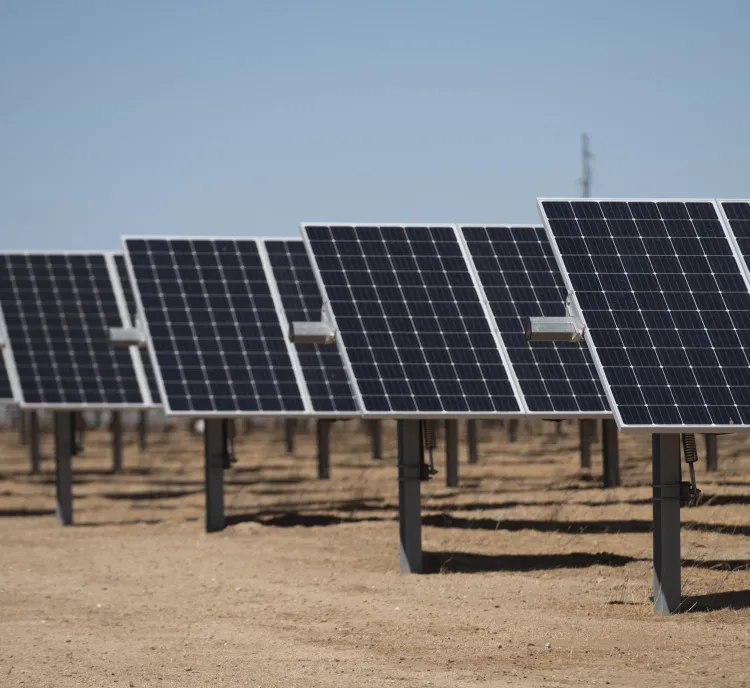 Rows of solar panels installed in a desert landscape under a clear blue sky.