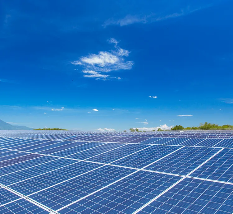 Large field of solar panels under a clear blue sky with a few clouds, capturing sunlight for renewable energy generation.