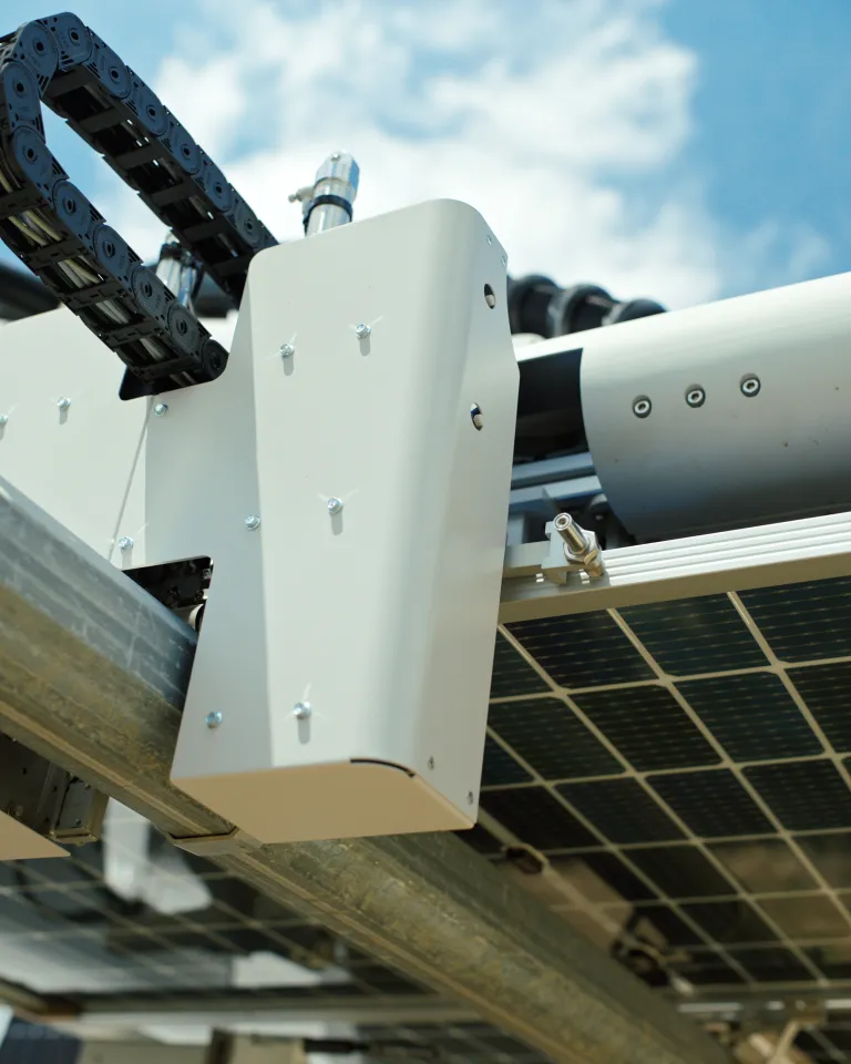 Close-up of a solar panel installation with metal supports and cable management system under a blue sky.
