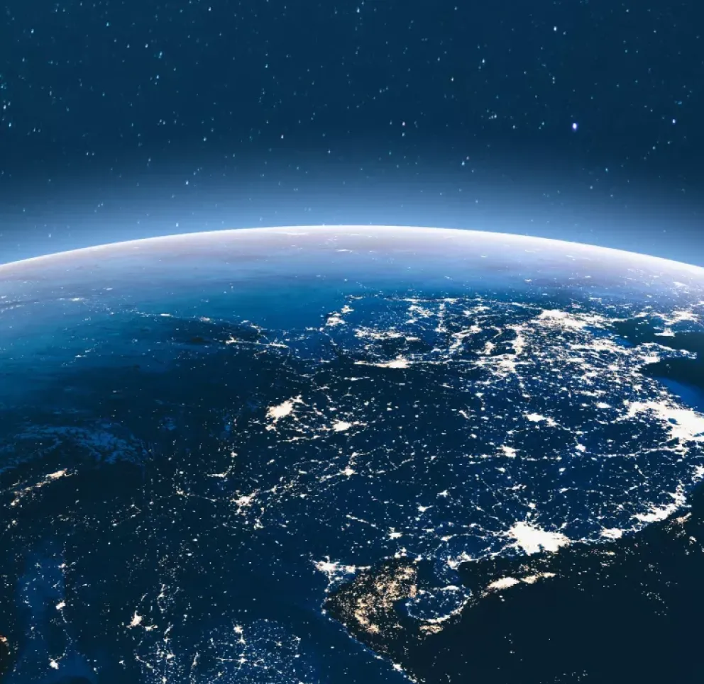 A view of Earth from space at night, showing illuminated city lights across a continent under a starry sky.