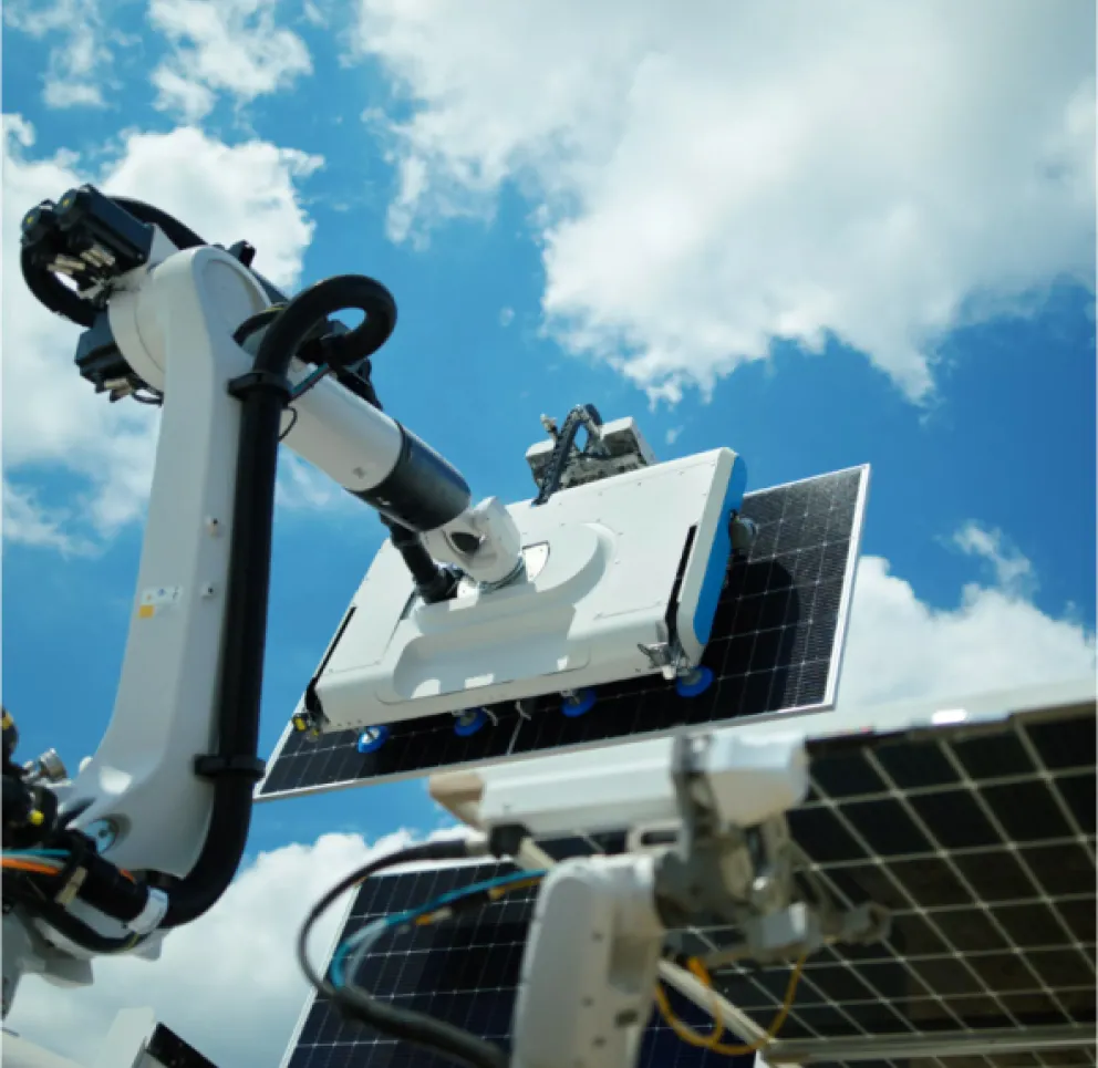 A robotic arm cleaning a solar panel under a blue sky with clouds.