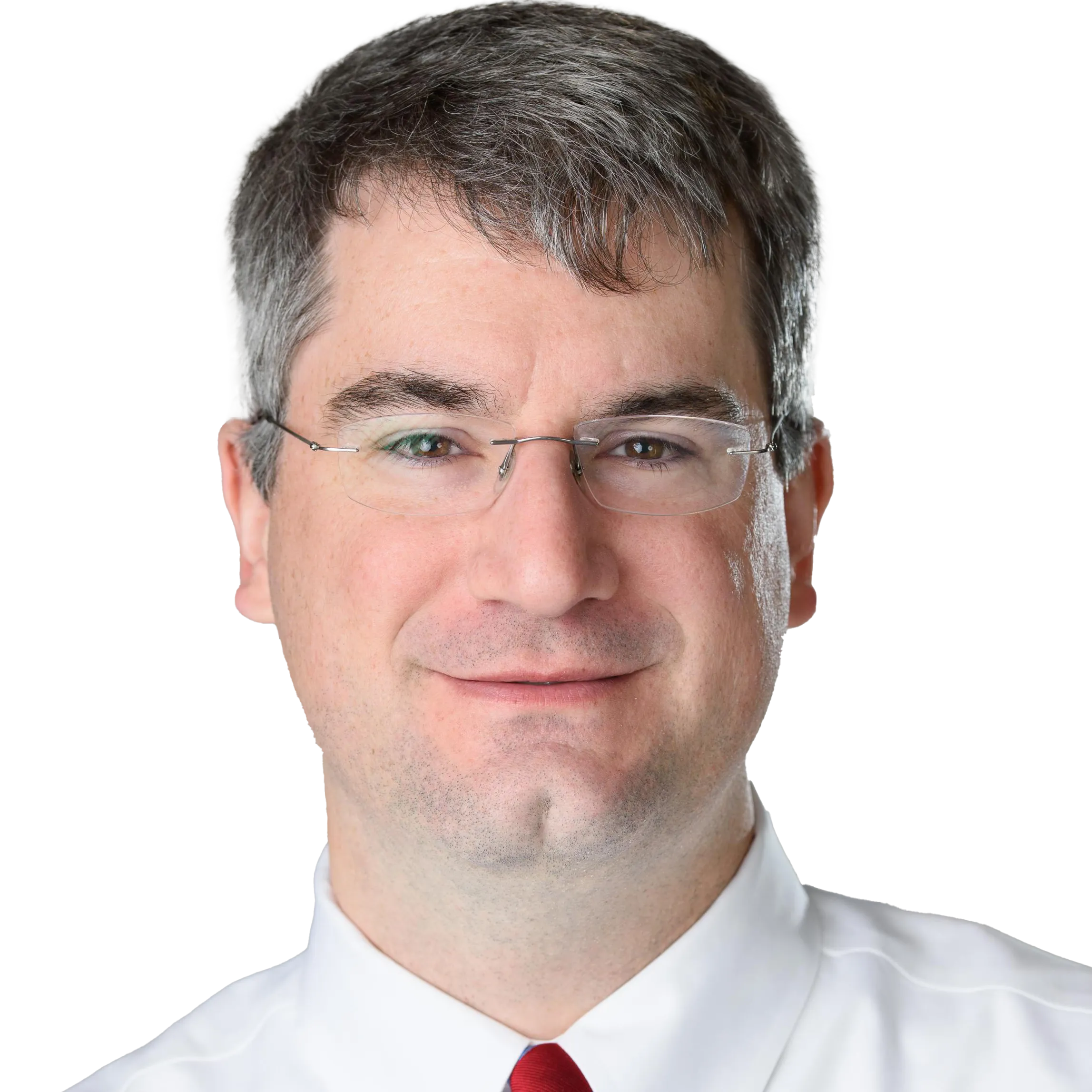 Portrait of a man with short gray hair and glasses, wearing a white shirt and red tie, smiling slightly.