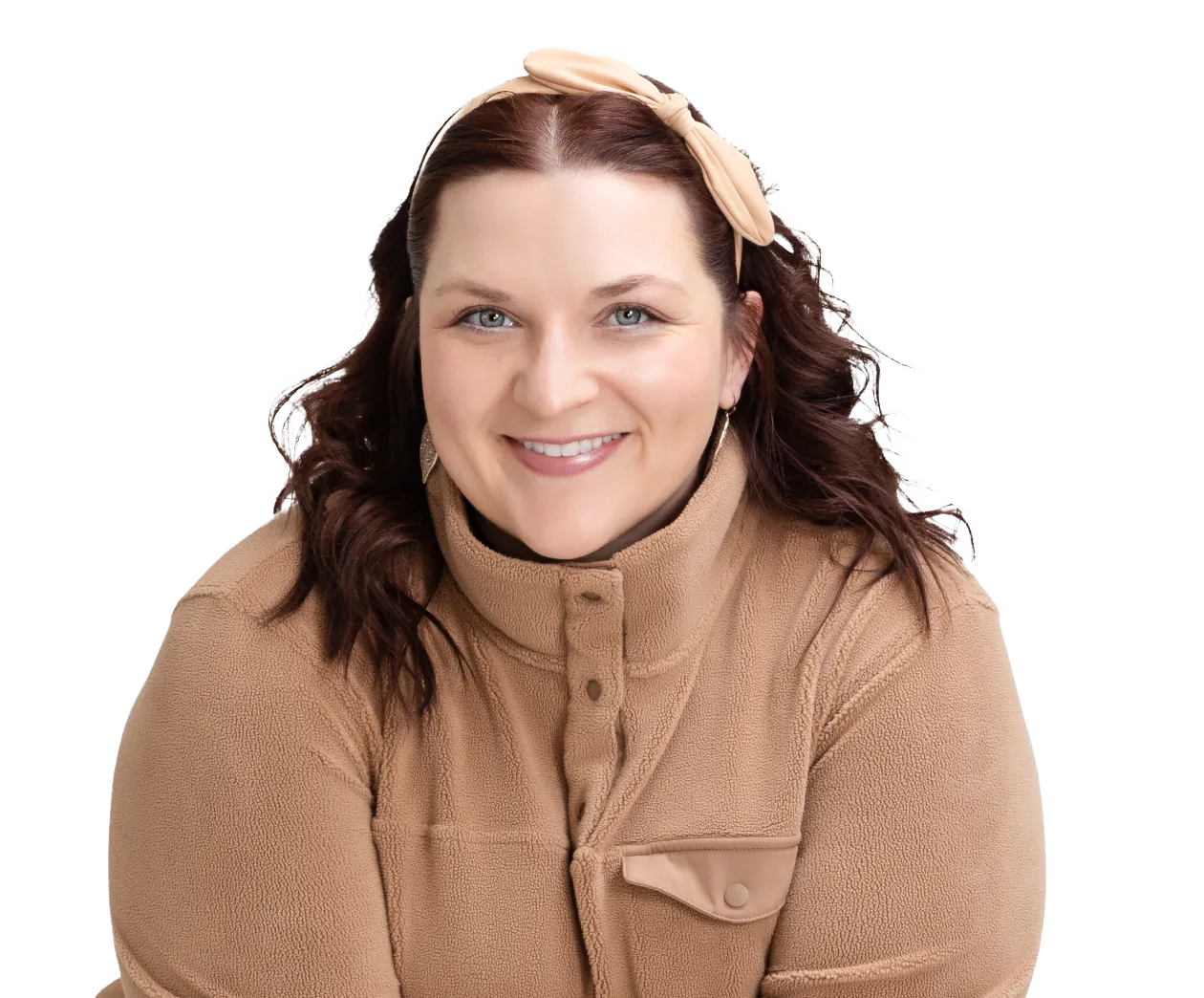 Woman with wavy brown hair wearing a tan fleece jacket and a matching tan headband, smiling at the camera against a white background.